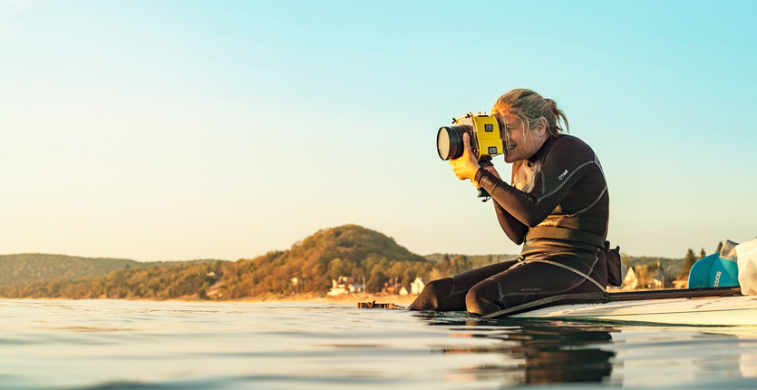 woman sitting on surf board in the water and taking a picture